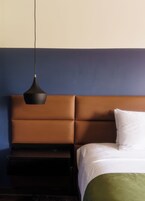 Una cama con cabecera, una mesita de noche y una lámpara colgante.