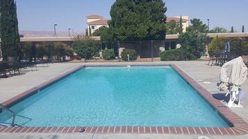 Een seizoensgebonden buitenzwembad en ligstoelen