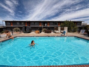 A swimming pool with lounge chairs and a building in the background.