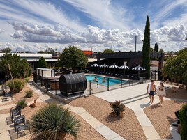 Un área de piscina con sillas de descanso y sombrillas, rodeada de jardines ajardinados y un edificio identificado como 'THE WESLEY'.