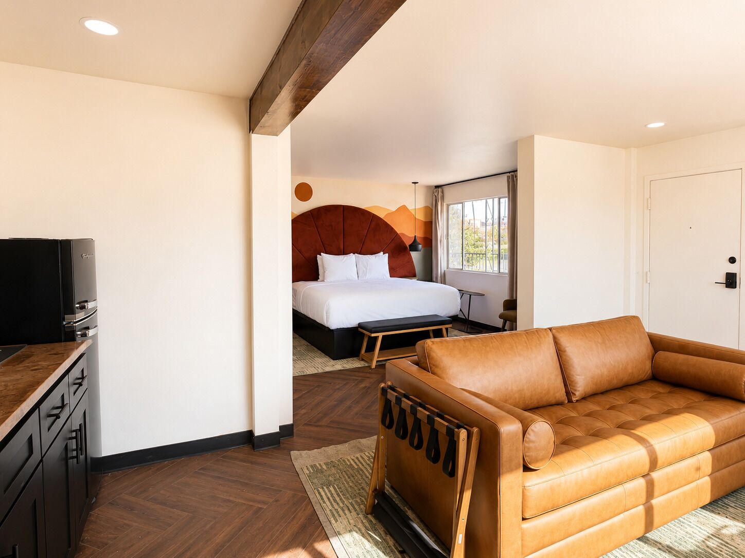 A modern hotel room with a bed, a sofa, a TV, and a desk.