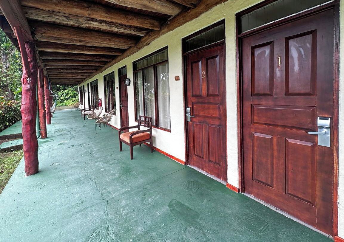 A covered porch with wooden pillars, a bench, and two doors.