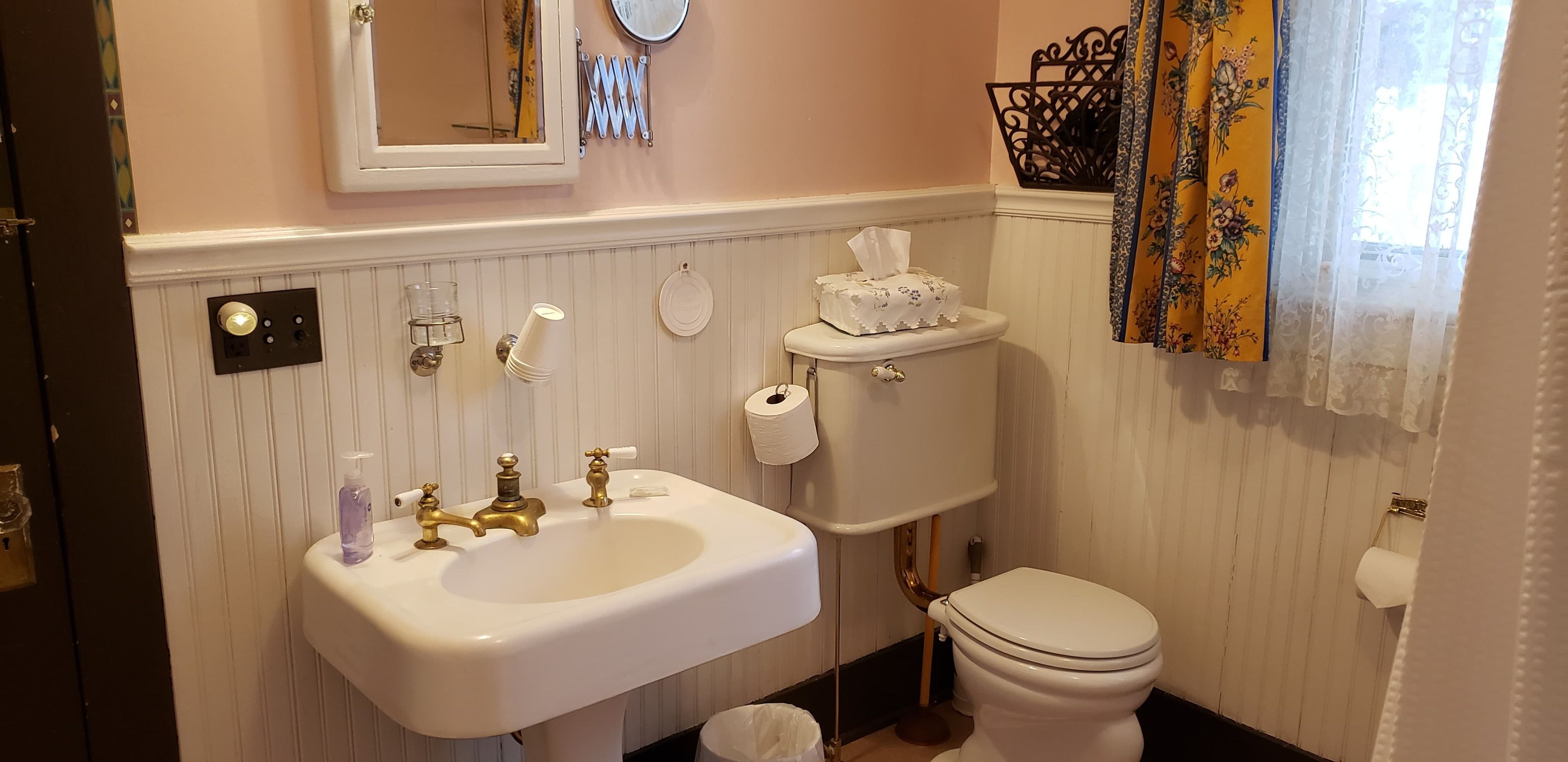 Ein Badezimmer mit Waschbecken, goldenen Wasserhähnen, Toilette und Spiegel.
