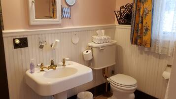 Ein Badezimmer mit Waschbecken, goldenen Wasserhähnen, Toilette und Spiegel.