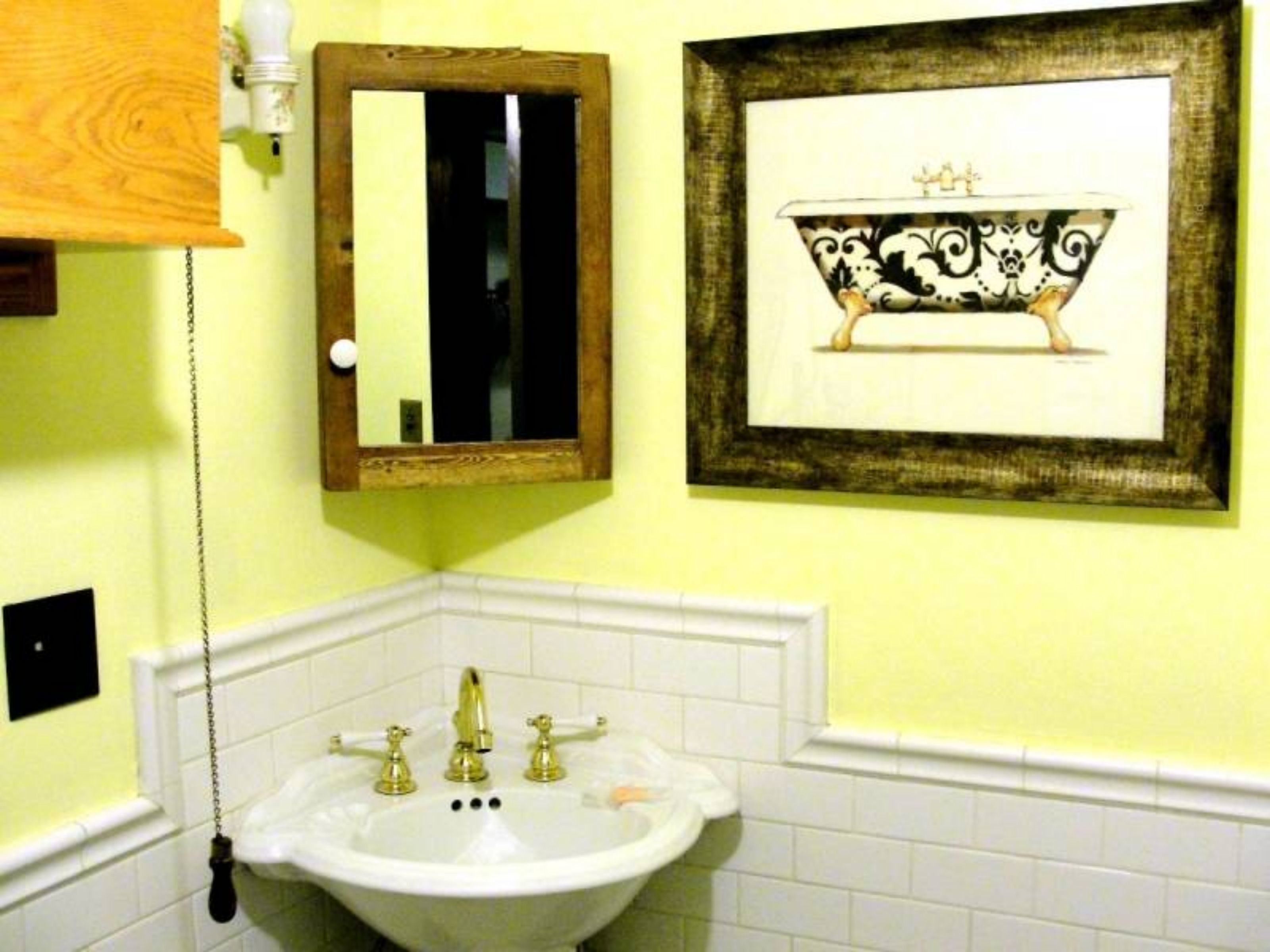 A bathroom with a white sink, a mirror, and a framed picture of a bathtub.