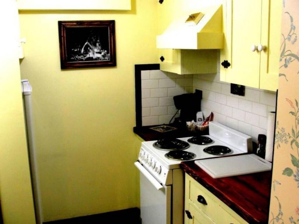 Cocina pequeña con estufa blanca, gabinetes amarillos y una encimera.