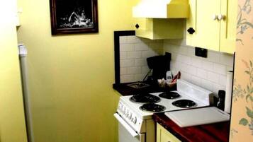 Cocina pequeña con estufa blanca, gabinetes amarillos y una encimera.