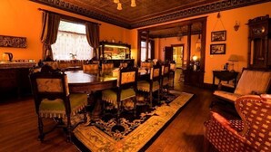 A traditional room with a wooden dining table, chairs, and a patterned rug.
