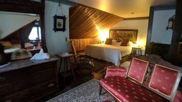 Ein Zimmer mit einem Bett, einem Holzschrank, einem rot gepolsterten Sofa und einem gemusterten Teppich.