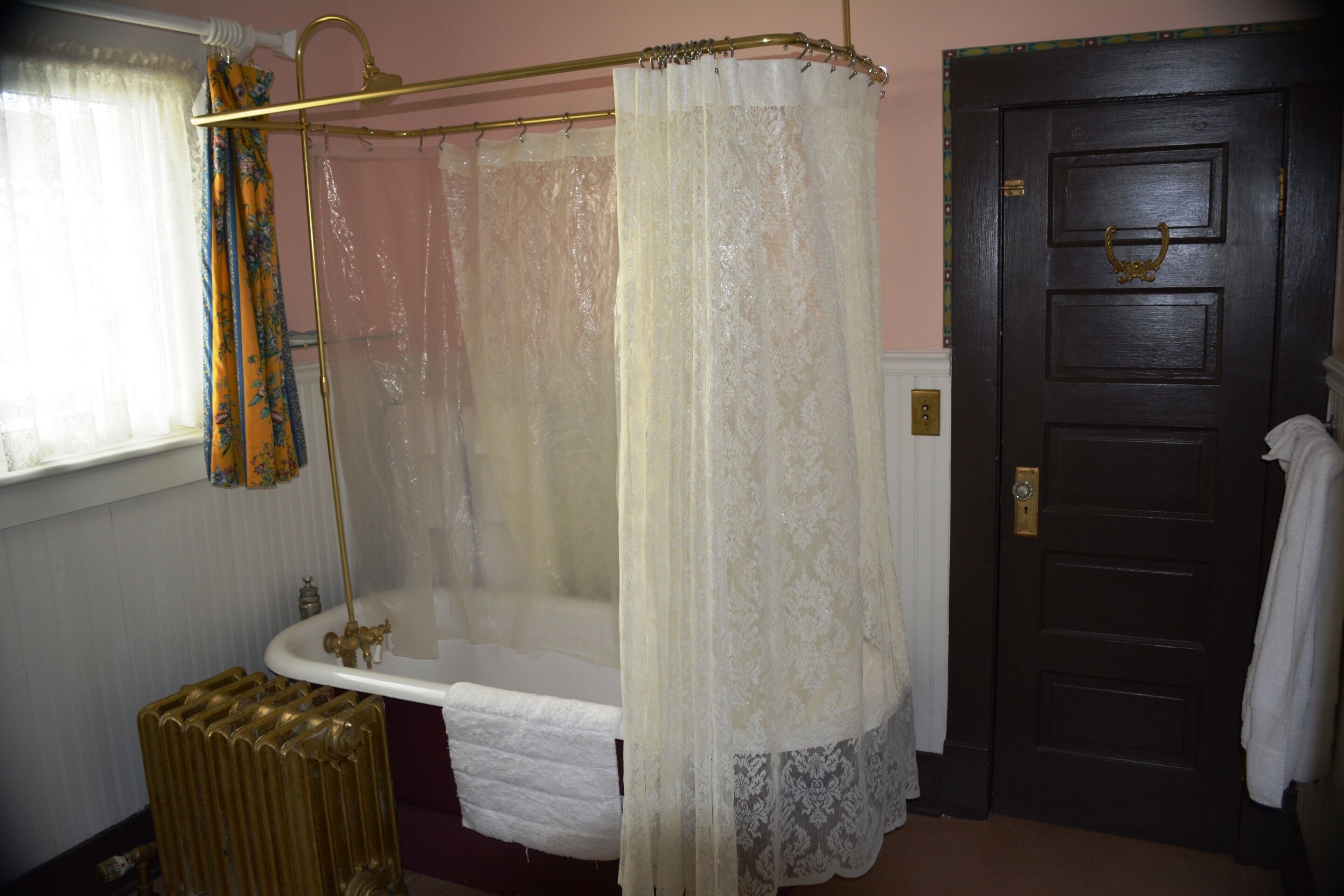 Un baño con bañera, cortina de ducha, radiador y puerta.