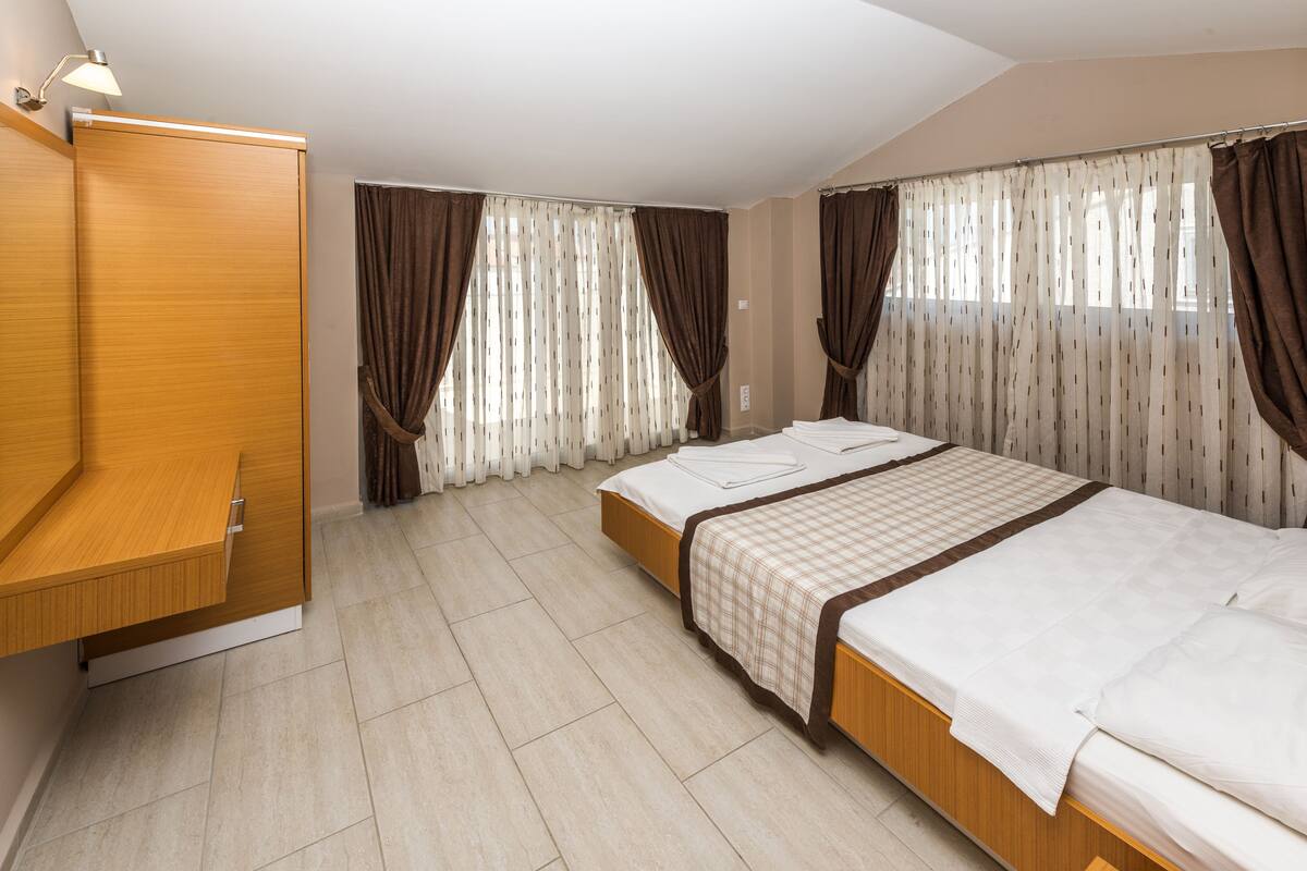 Habitación de hotel con dos camas, un armario y un escritorio.