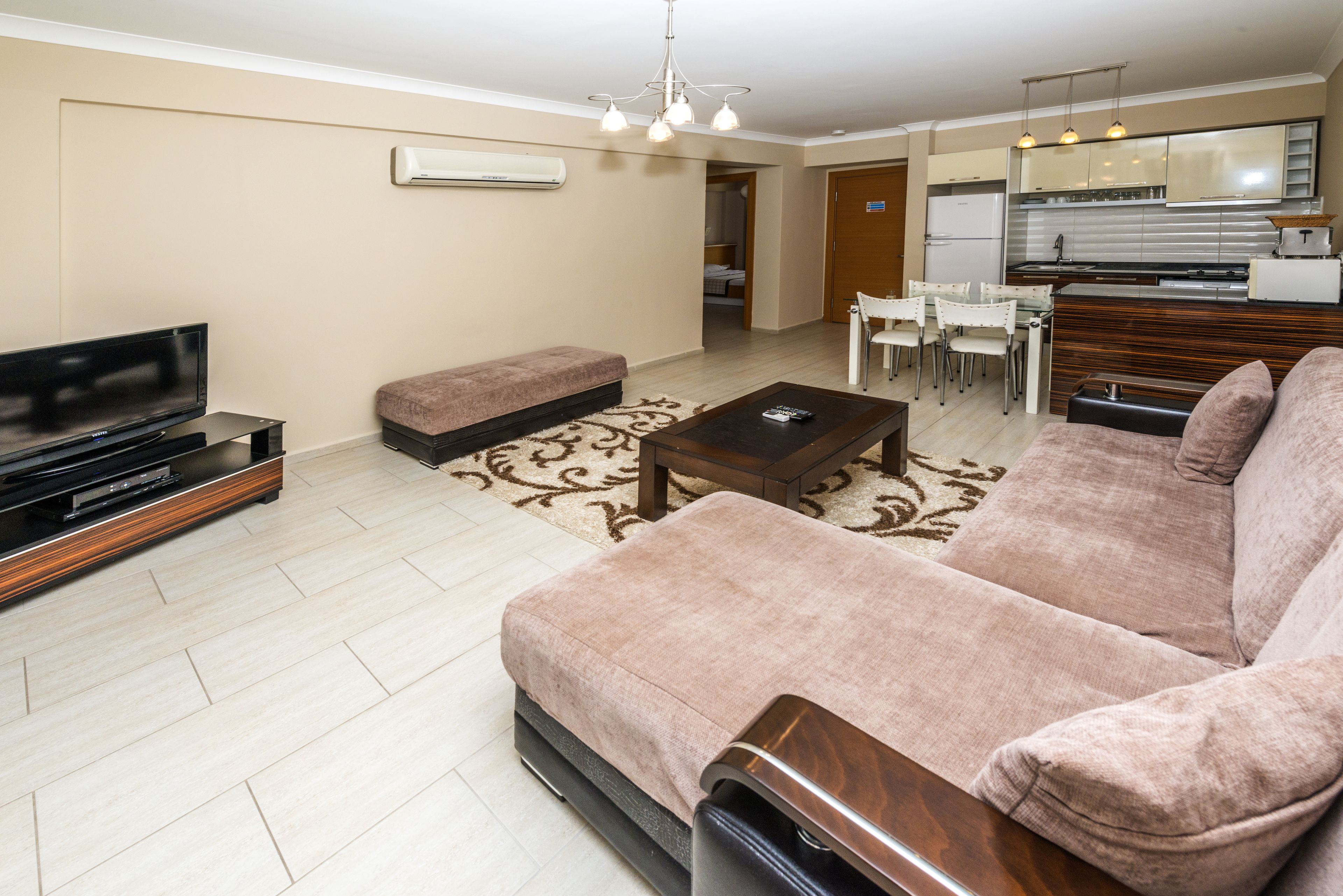 A modern living room with a large sofa, a coffee table, a TV, and a dining area with chairs.