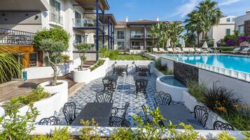 Zona junto a la piscina con mobiliario exterior y vistas a ella.