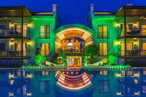 Ein mehrstöckiges Hotel mit Innenhof, Balkonen und einem Pool, der das Gebäude widerspiegelt.