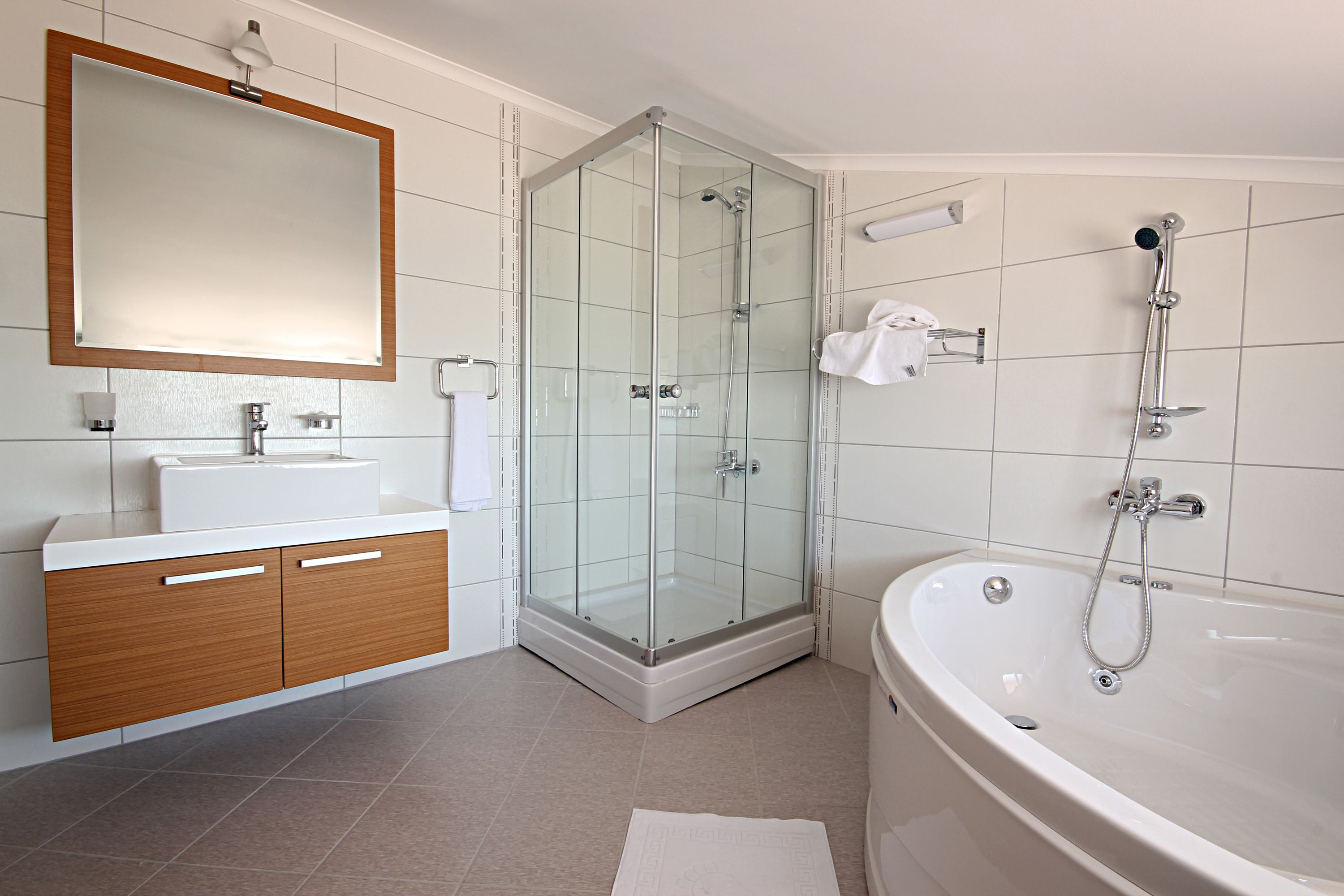 A modern bathroom with a glass-enclosed shower, a freestanding bathtub, and a vanity with a mirror.