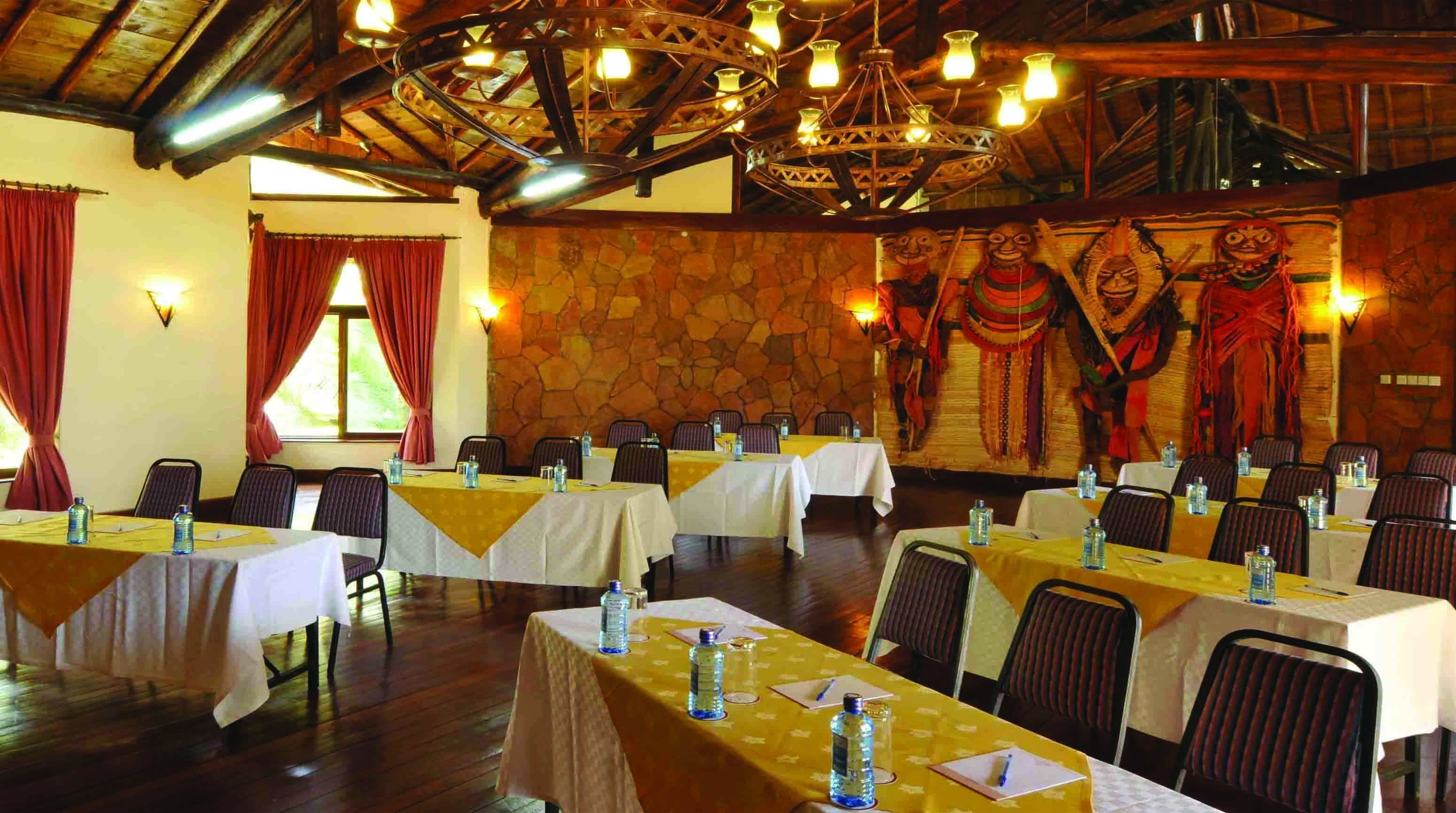 A conference room with multiple tables, chairs, and a stone wall with traditional decorations.