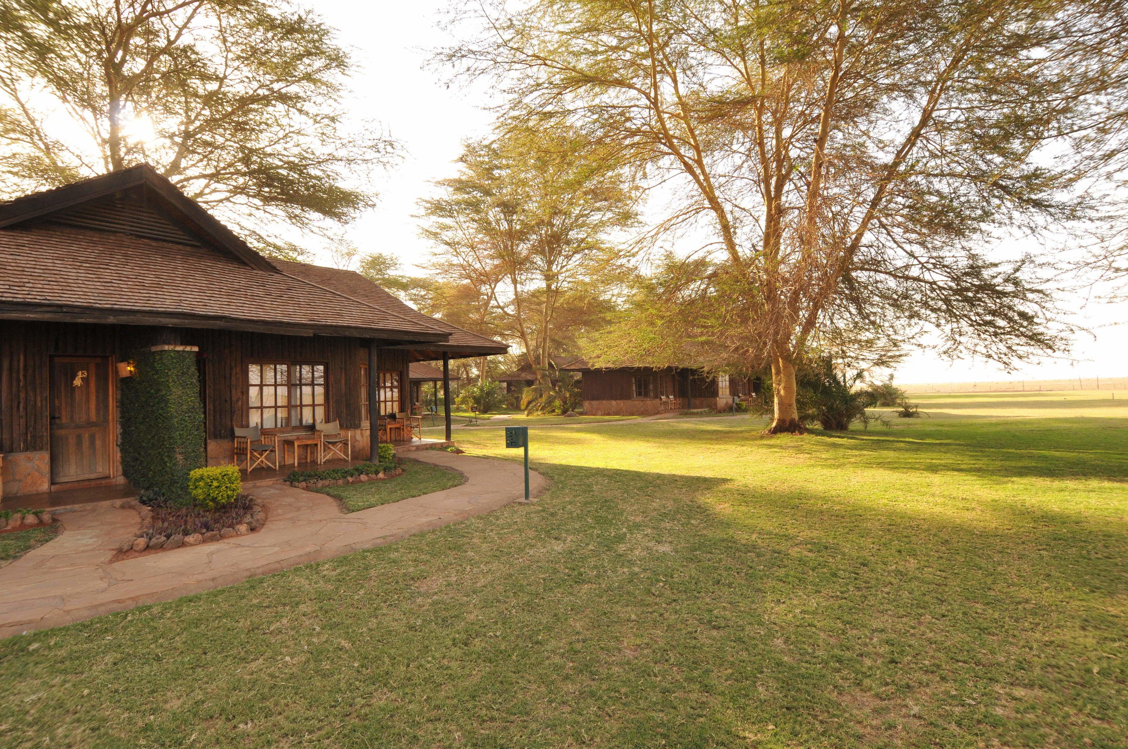 A rustic lodge with a covered porch and outdoor seating, surrounded by a well-maintained lawn and trees.