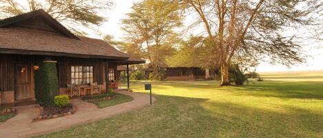 A rustic lodge with a covered porch and outdoor seating, surrounded by a well-maintained lawn and trees.