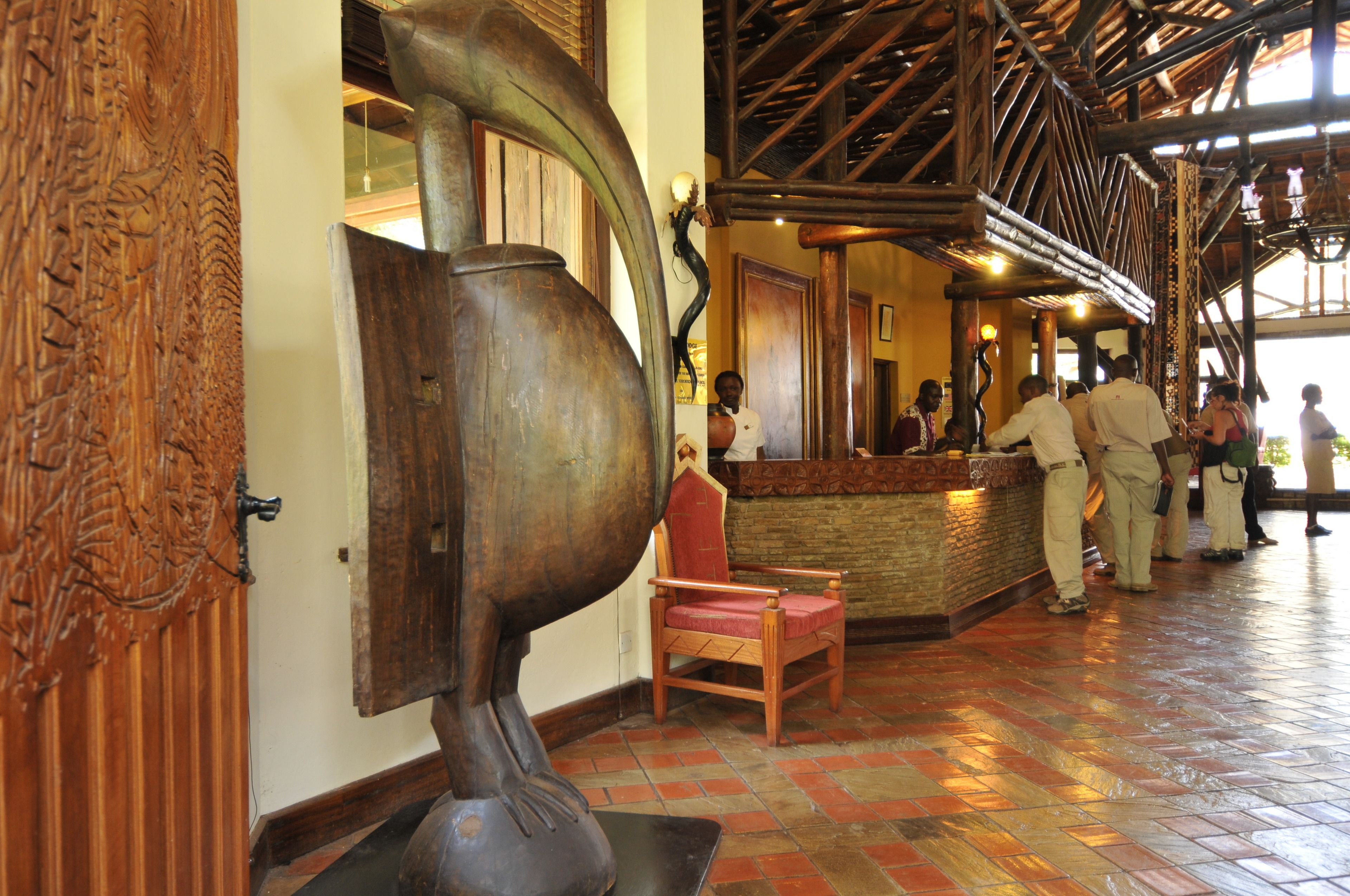 A lobby with a wooden reception desk, a chair, and a large metal sculpture.