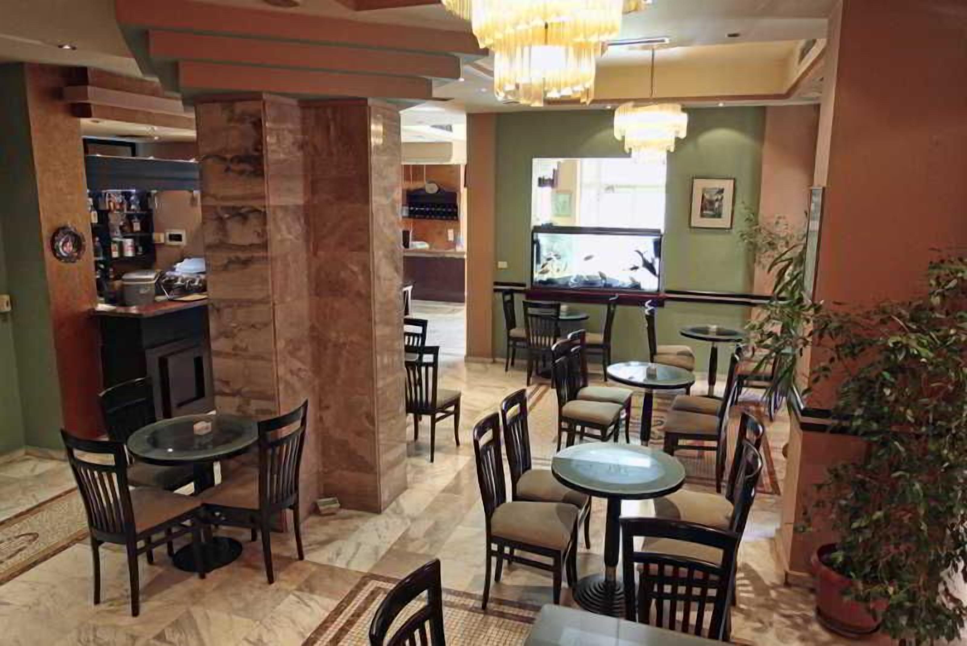 A hotel lobby with multiple seating areas, a bar, and a television screen.