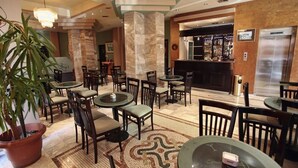 Eine Hotelhalle mit mehreren Sitzbereichen, einer Bar und einer Rezeption.