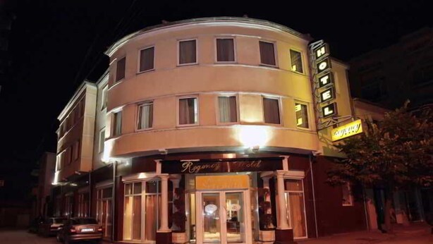 Ein Hotel mit geschwungener Fassade, einem gut sichtbaren Eingang und einem Schild.