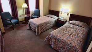 Ein Hotelzimmer mit zwei Betten, einem Schreibtisch, einem Stuhl und einer Lampe.