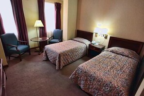 A hotel room with two beds, a desk, a chair, and a lamp. - Regency Hotel (Korçë)
