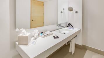 Un baño moderno con tocador blanco, dos lavamanos, un espejo grande y una puerta de madera.