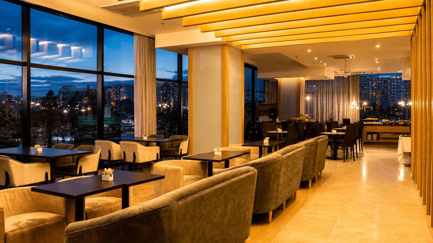 A modern restaurant with high ceilings, large windows, and a city view.