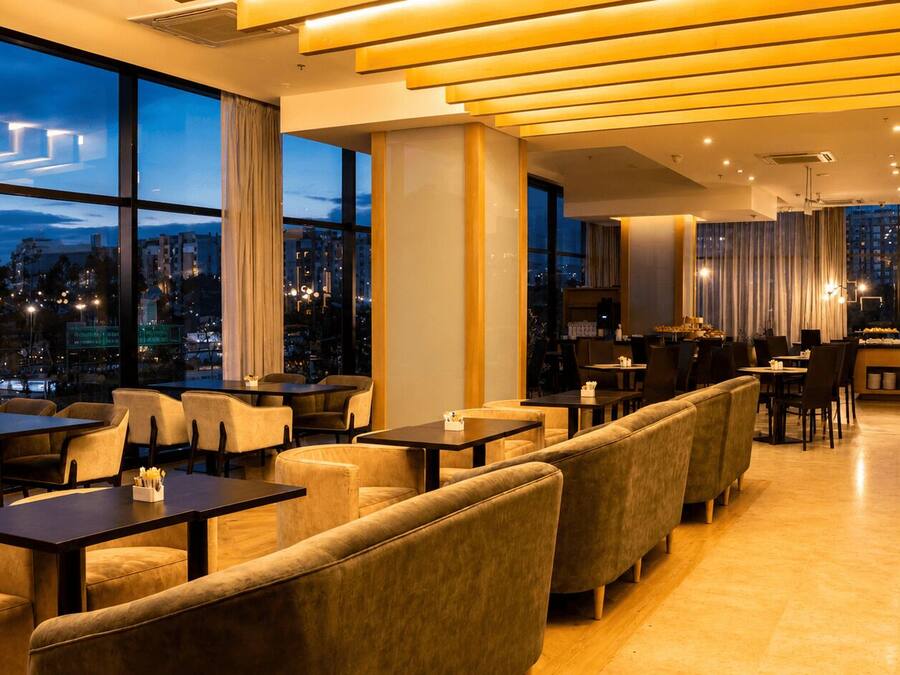 Un restaurante moderno con techos altos, ventanas amplias y vistas a la ciudad.