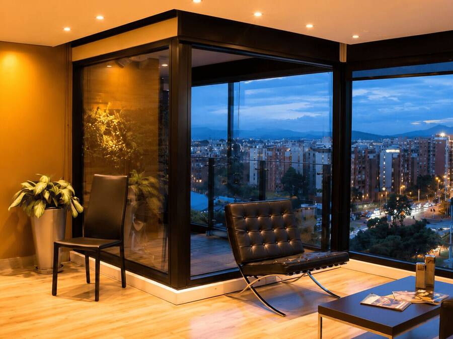 A modern living room with a large window, a sofa, a chair, and a potted plant.
