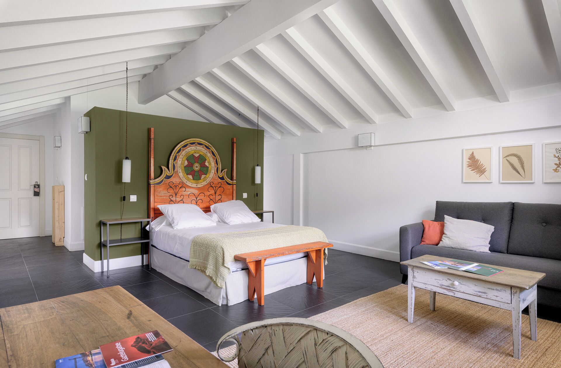 A modern bedroom with a bed, a sofa, a coffee table, and a unique headboard.