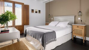 Une chambre à coucher avec un lit, une table de chevet, une commode et une plante en pot.