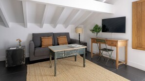 Un salon moderne comprenant un canapé, une table basse, un téléviseur et un bureau.