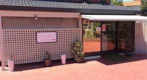 A reception area with a sign for the Cleveland Visitor Villa Motel, a lattice fence, potted plants, and a door with a glass panel.
