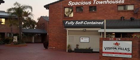 A brick building with a sign for 'Spacious Townhouses' and 'Fully Self-Contained'.