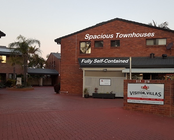 A brick building with a sign for 'Spacious Townhouses' and 'Fully Self-Contained'.