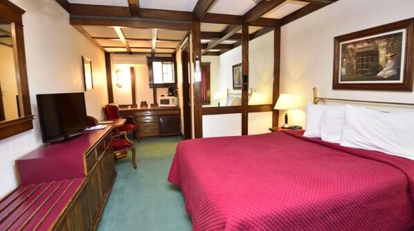 A hotel room with a bed, a desk, a television, a mirror, and a painting on the wall.
