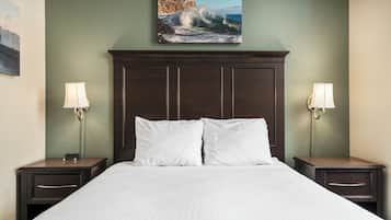 A hotel room with a large bed, two nightstands, and a painting of a coastal scene above the bed.
