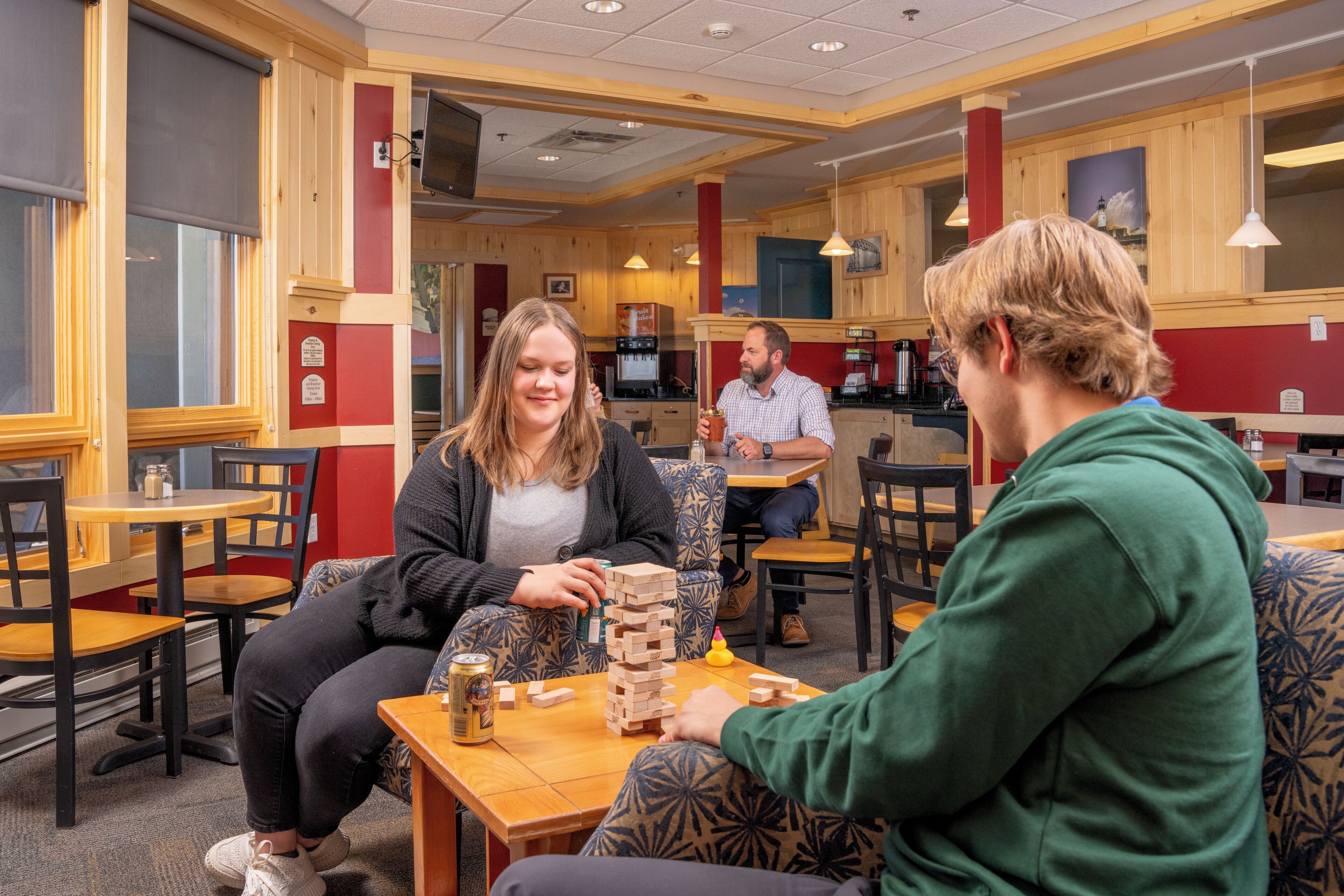 Un espace intérieur accueillant avec des tables et des chaises en bois, une machine à café et un juke-box.