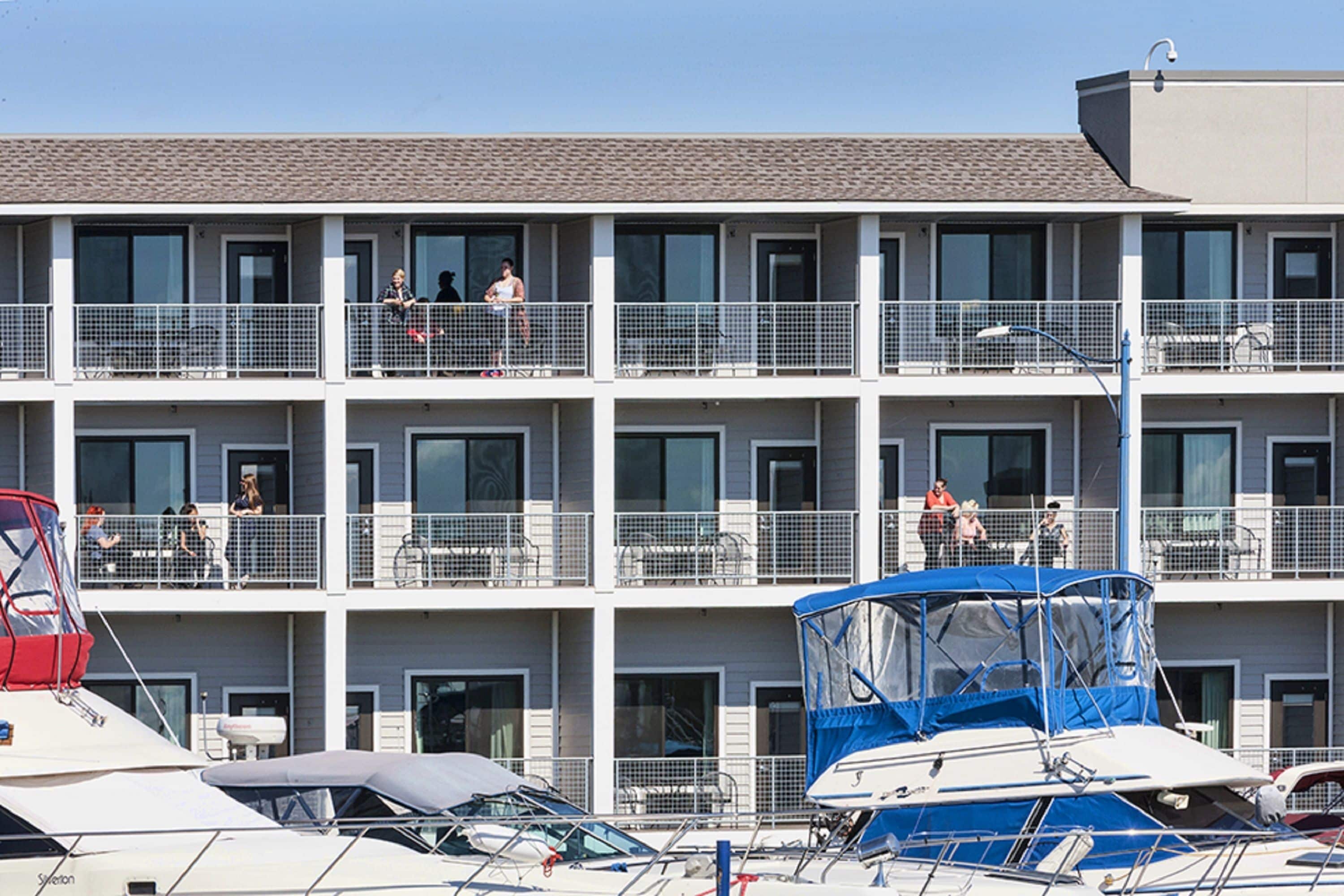 A multi-story hotel with balconies, a covered boat area, and a clear sky.