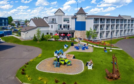 A hotel with a playground, outdoor seating, and a large building with multiple balconies.