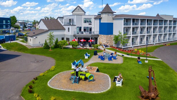 A hotel with a playground, outdoor seating, and a large building with multiple balconies. - Park Point Marina Inn (Duluth)