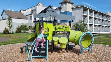 A playground with a slide, climbing area, and a green tunnel.
