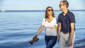A couple walking on a beach with the ocean in the background. - Park Point Marina Inn (Duluth)