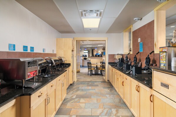 A modern kitchen with granite countertops, wooden cabinets, and a stone floor.