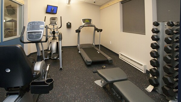 A gym with cardio machines, weight benches, and dumbbells.