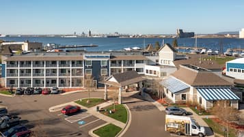 A multi-story building with a parking lot and a marina in the background.