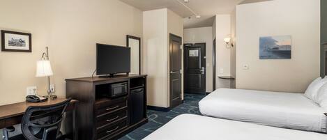 A hotel room with a bed, desk, chair, television, and a door leading to another room.